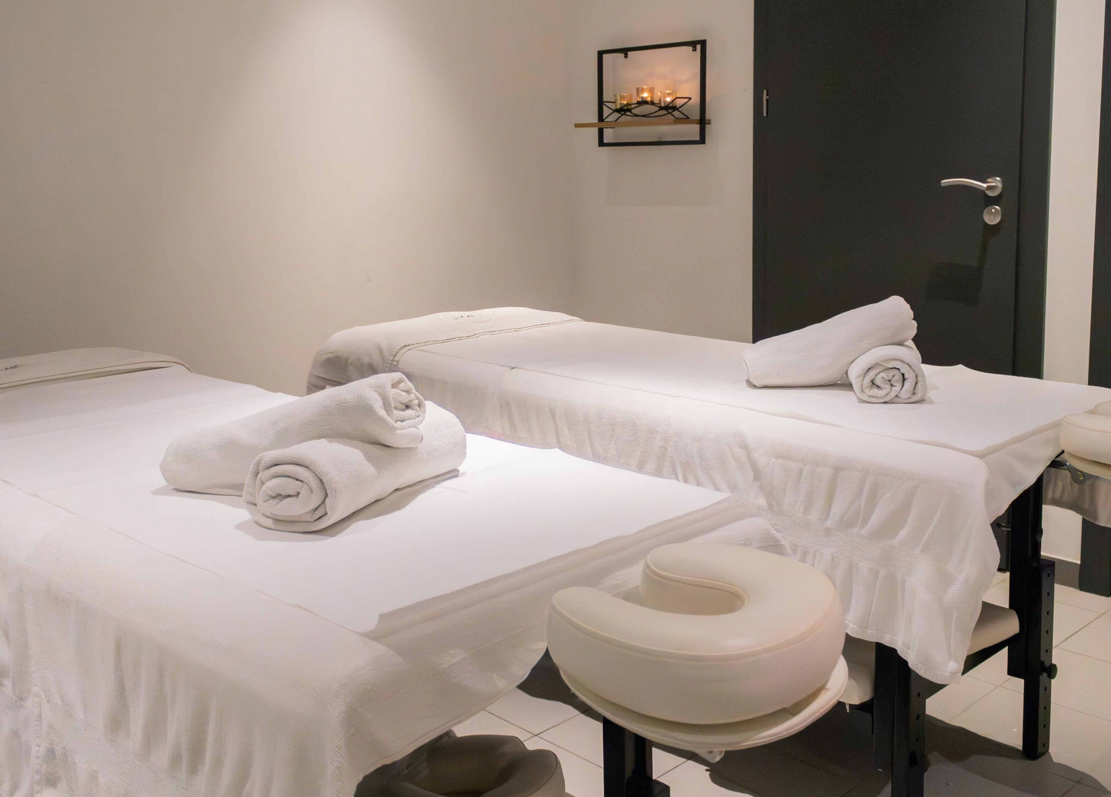 Relaxing spa room at AMIS @ The Embassy Hotel, Valletta, MT, featuring two massage tables with fresh towels.