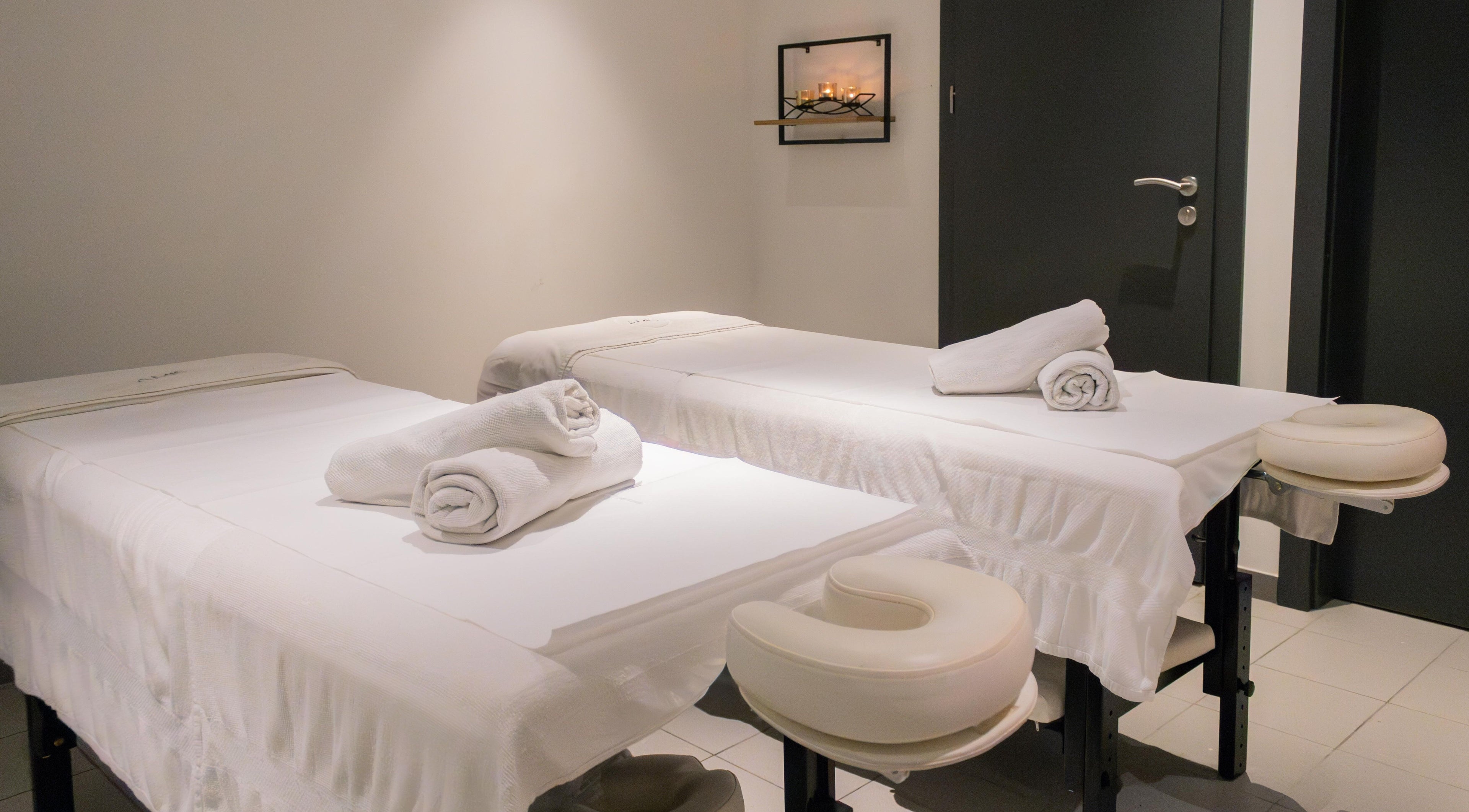 Relaxing spa room at AMIS @ The Embassy Hotel, Valletta, MT, featuring two massage tables with fresh towels.