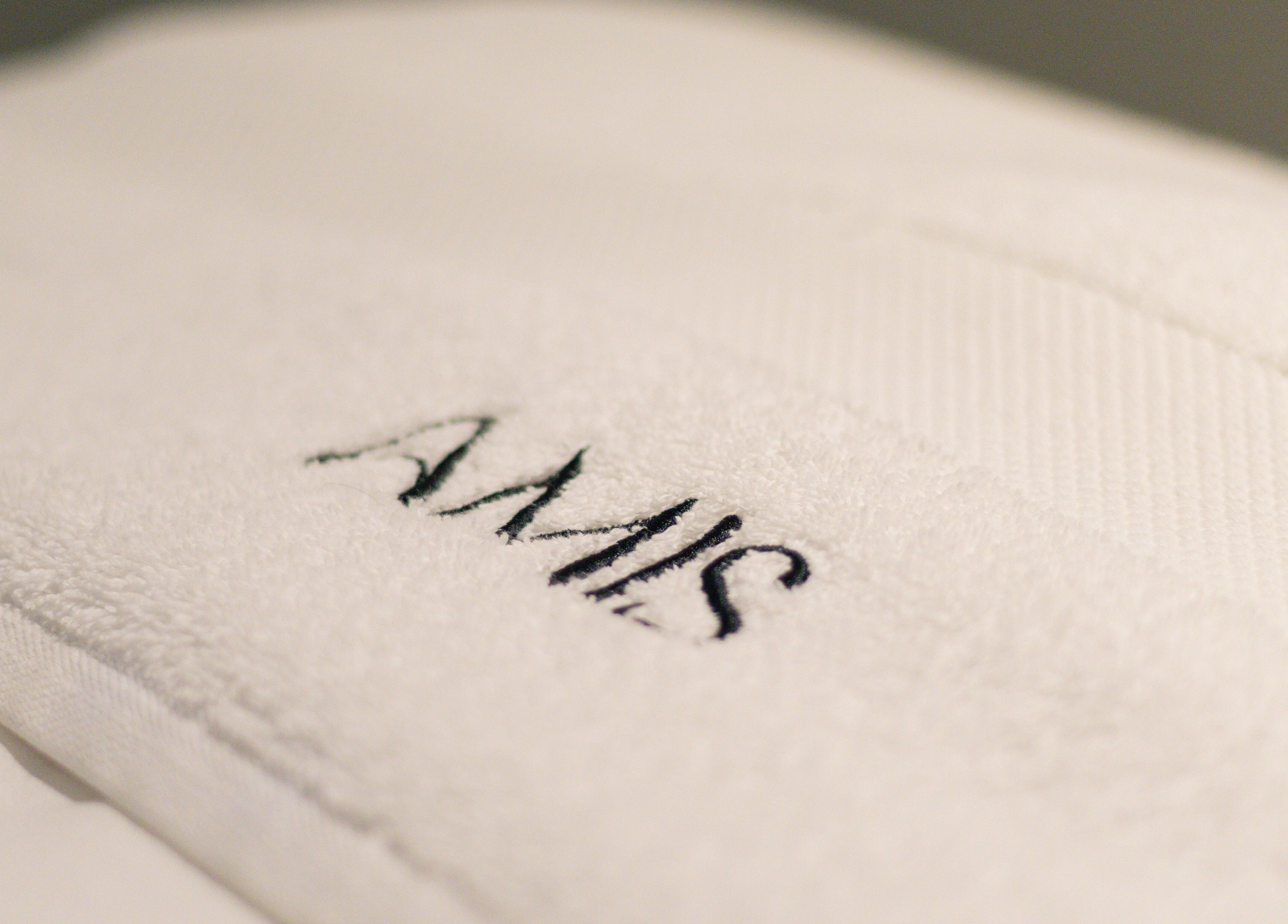 A plush white towel with AMIS logo at AMIS @ The Embassy Hotel, Valletta, MT.