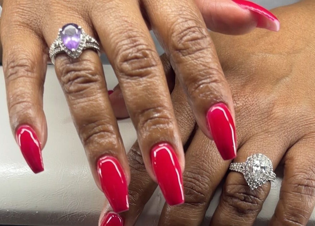 Elegant red manicured nails at Reaper Nails in Marietta, Georgia, US, adorned with sparkling rings.