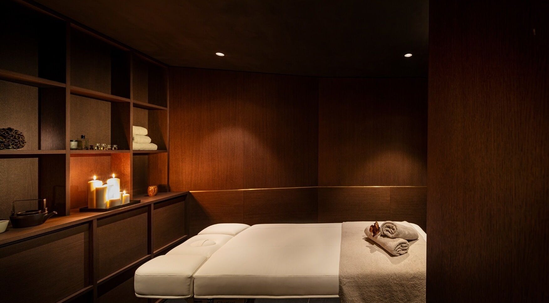 Луксозен масажен кабинет в Junó Hotel Sofia, София, Софийска област, BG със запалени свещи и бели кърпи.