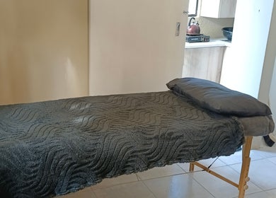 A cozy massage bed with a soft gray blanket at Sakura Beauty by Tarryn in East London, Eastern Cape, ZA.