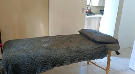 A cozy massage bed with a soft gray blanket at Sakura Beauty by Tarryn in East London, Eastern Cape, ZA.