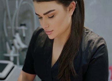 Skilled beautician at Masha Beauty Room, London, England, GB, in a sleek black uniform focused on her work.
