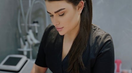 Skilled beautician at Masha Beauty Room, London, England, GB, in a sleek black uniform focused on her work.