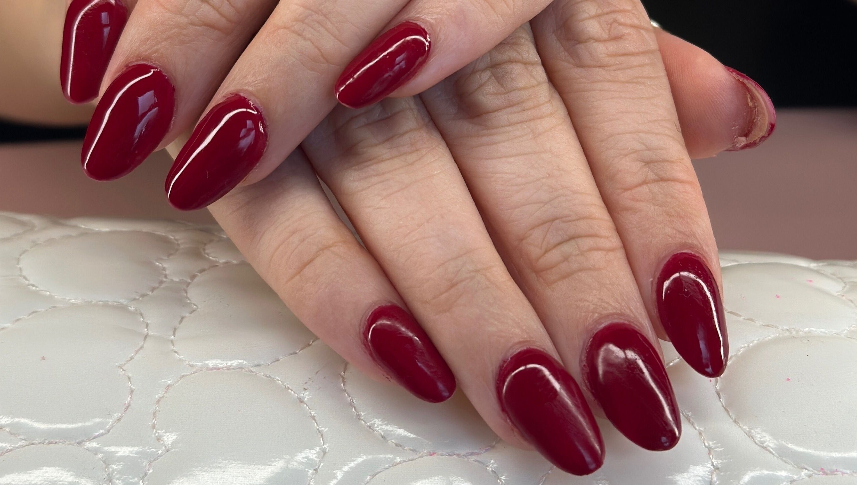 Elegant red nails at Glow Nails, Dublin, County Dublin, IE. Perfectly manicured hands on white cushion.