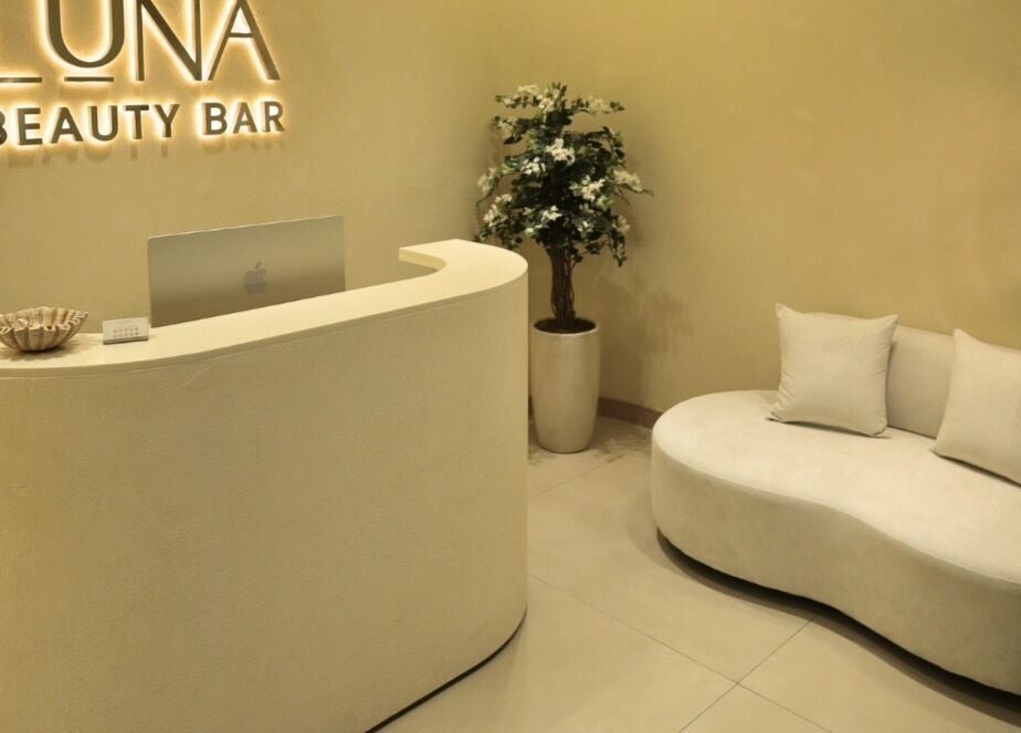 Reception area at Luna Beauty Bar, Dubai, Dubai, AE showcasing a stylish curved desk and comfy seating.