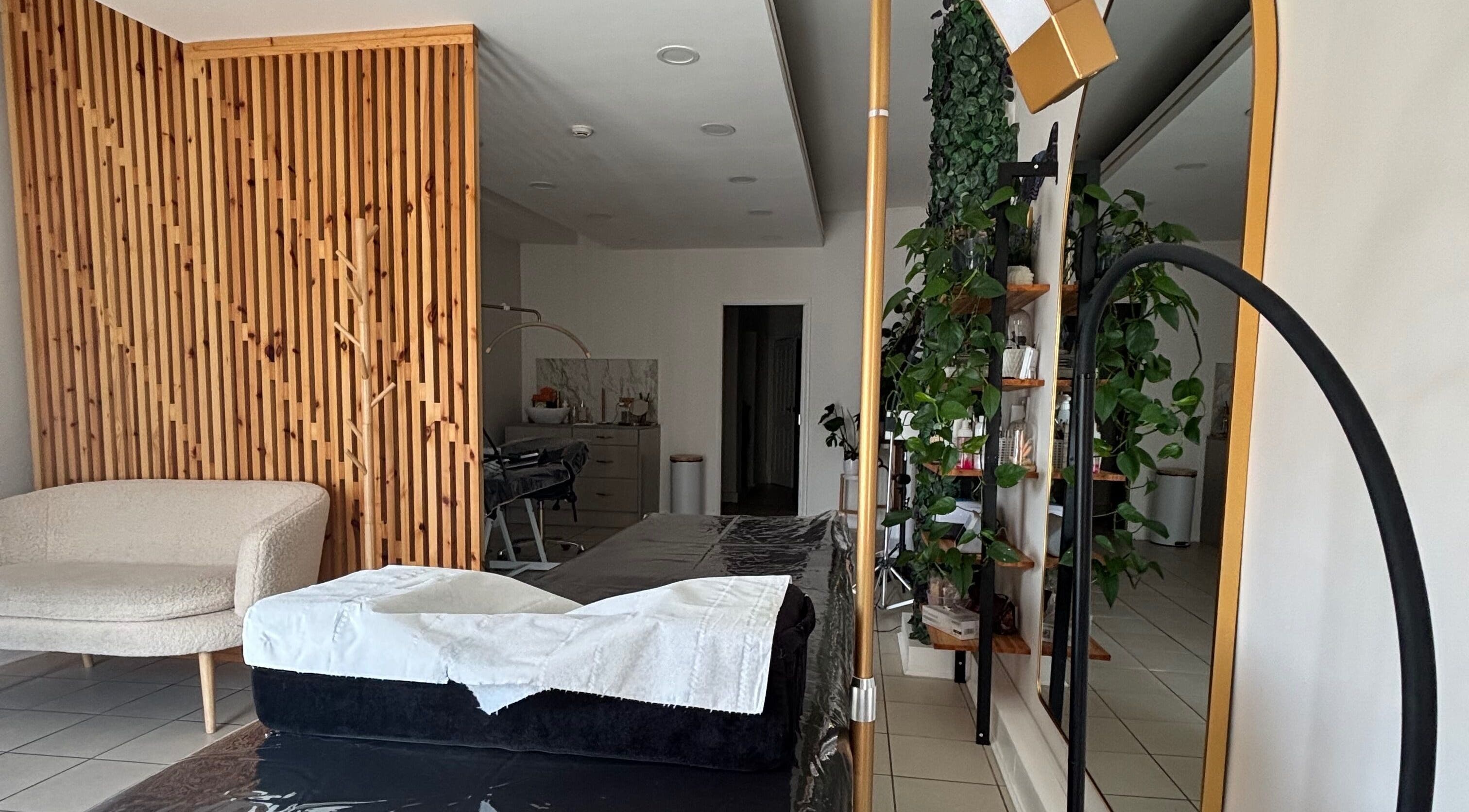 Elegant treatment room in Glamtime Iza Jeronim, Hull, England, GB, featuring modern decor and lush greenery.