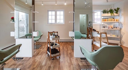 Intérieur moderne de Village Coiffure à Saint-Basile-le-Grand, Québec, CA, avec fauteuils verts et miroirs.