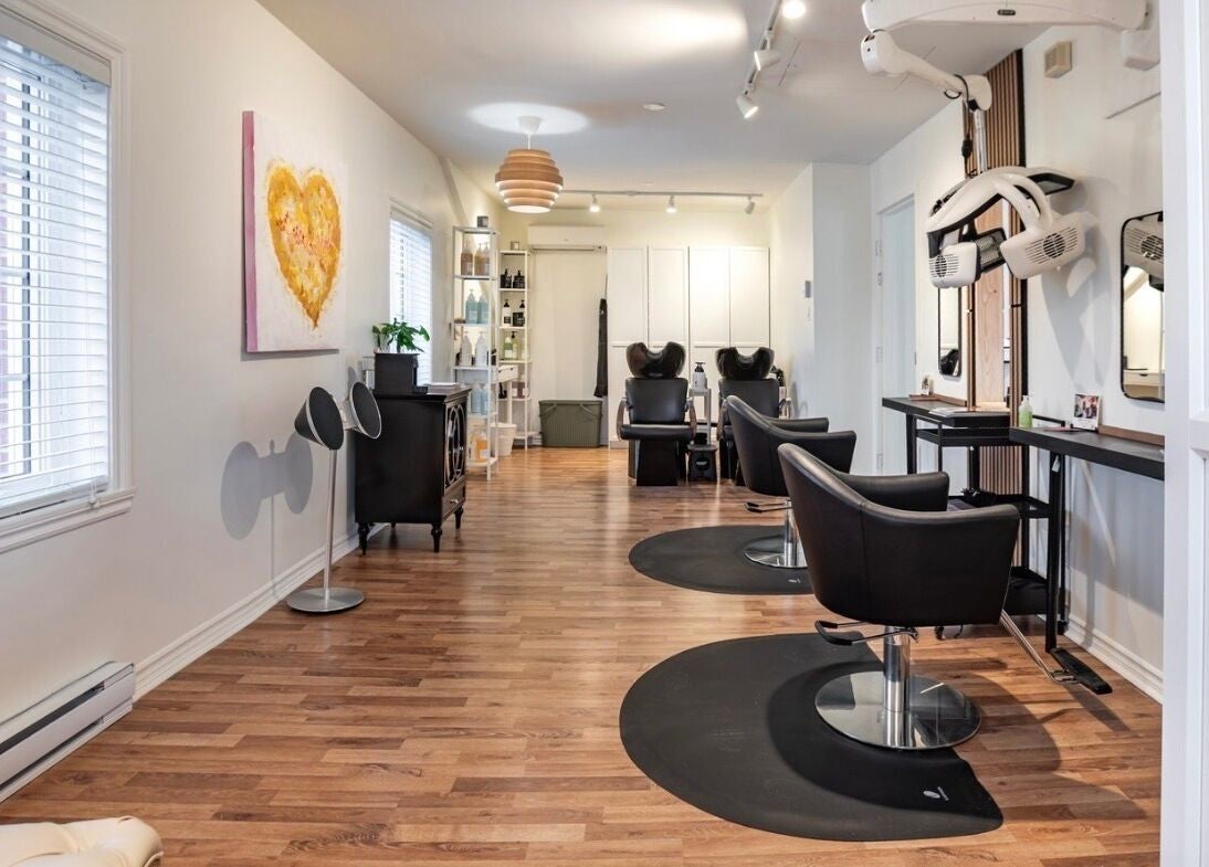 Intérieur élégant de Village Coiffure à Saint-Basile-le-Grand, Québec, CA avec chaises modernes et décor chaleureux.