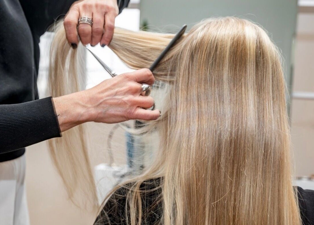 Styliste taillant des cheveux blonds à Village Coiffure, Saint-basile-le-grand, Québec, CA.