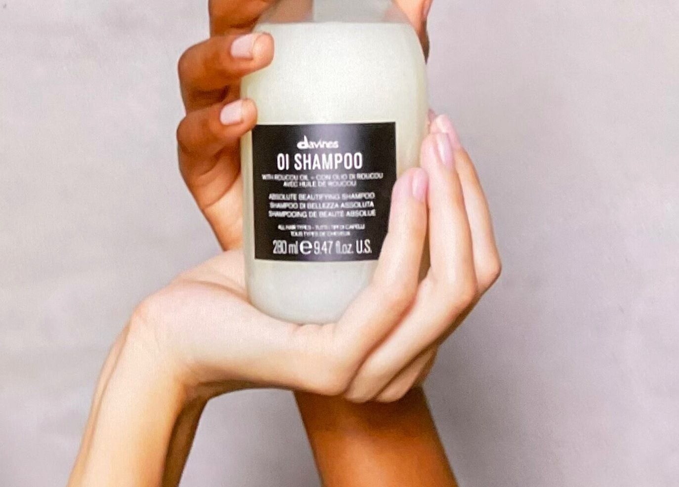 Shampooing OI tenu par deux mains à Village Coiffure, Saint-basile-le-grand, Québec, CA.