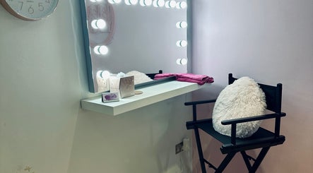Makeup vanity with mirror lights at Lux by Kristina, Cheltenham, England, GB. Elegant setup with chair and decor.