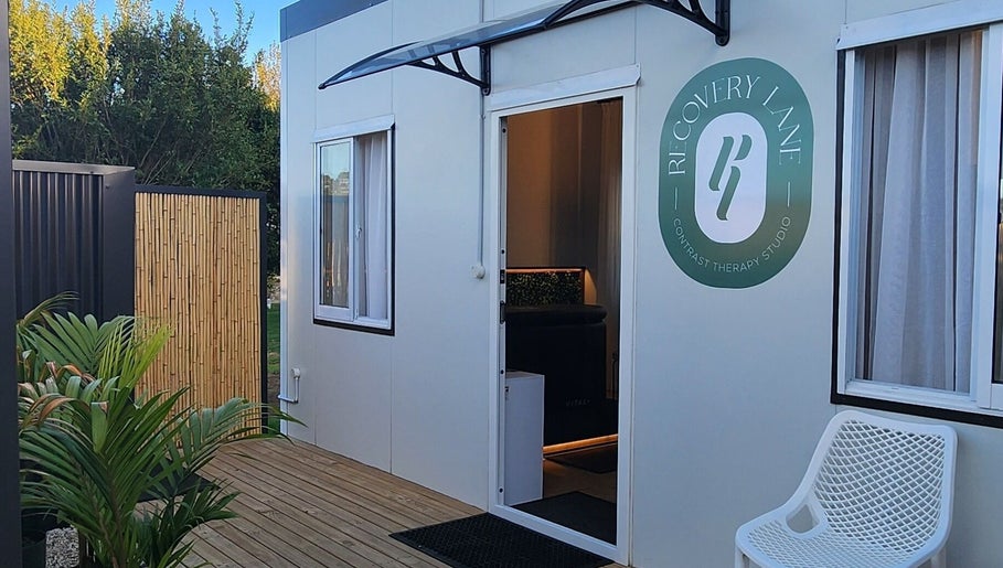 Entrance of Recovery Lane, a therapy studio in Waiuku, Auckland, NZ, with wooden deck and greenery.