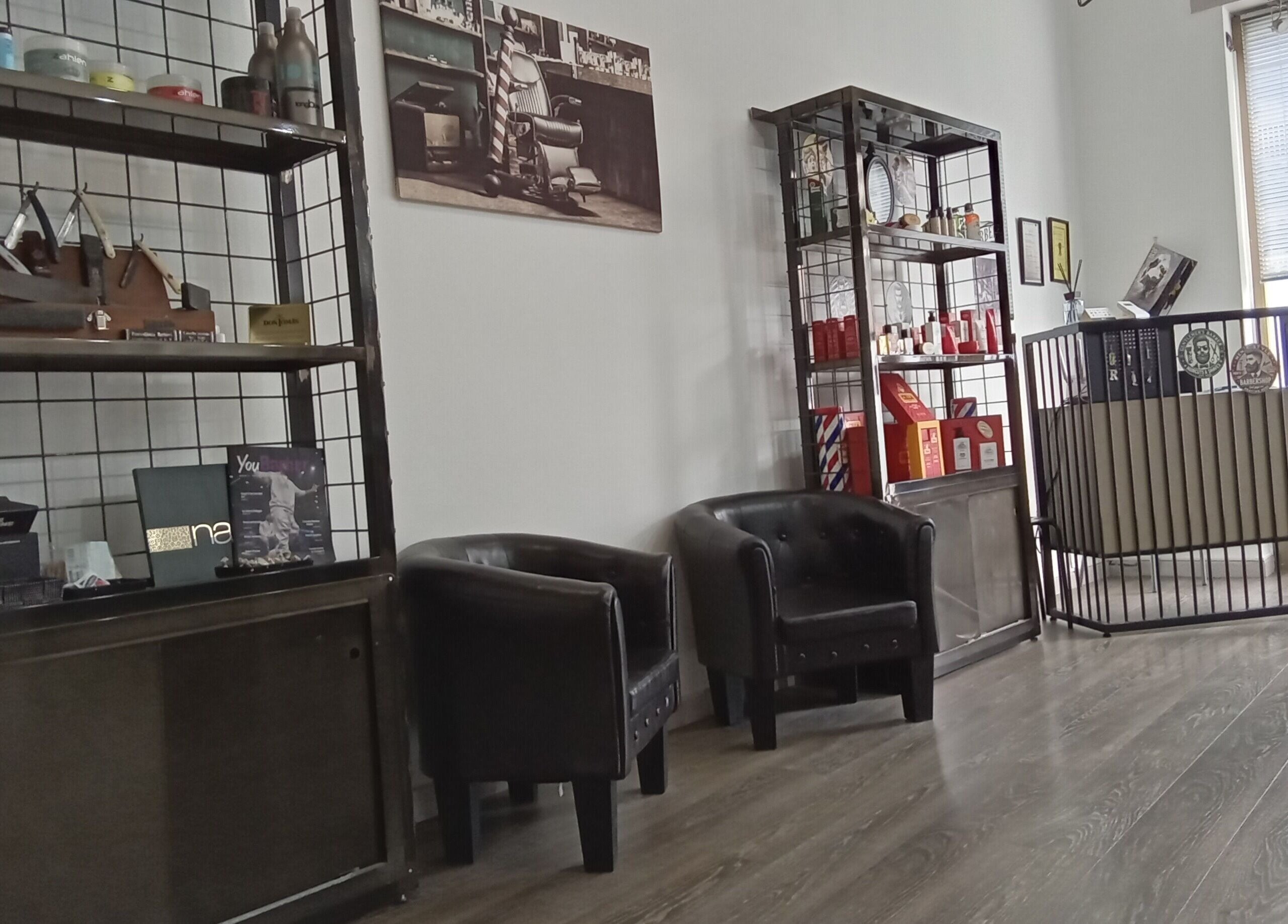Interno di Classic Barber a San Vittore Olona, Lombardia, IT, con poltrone e scaffali espositivi.