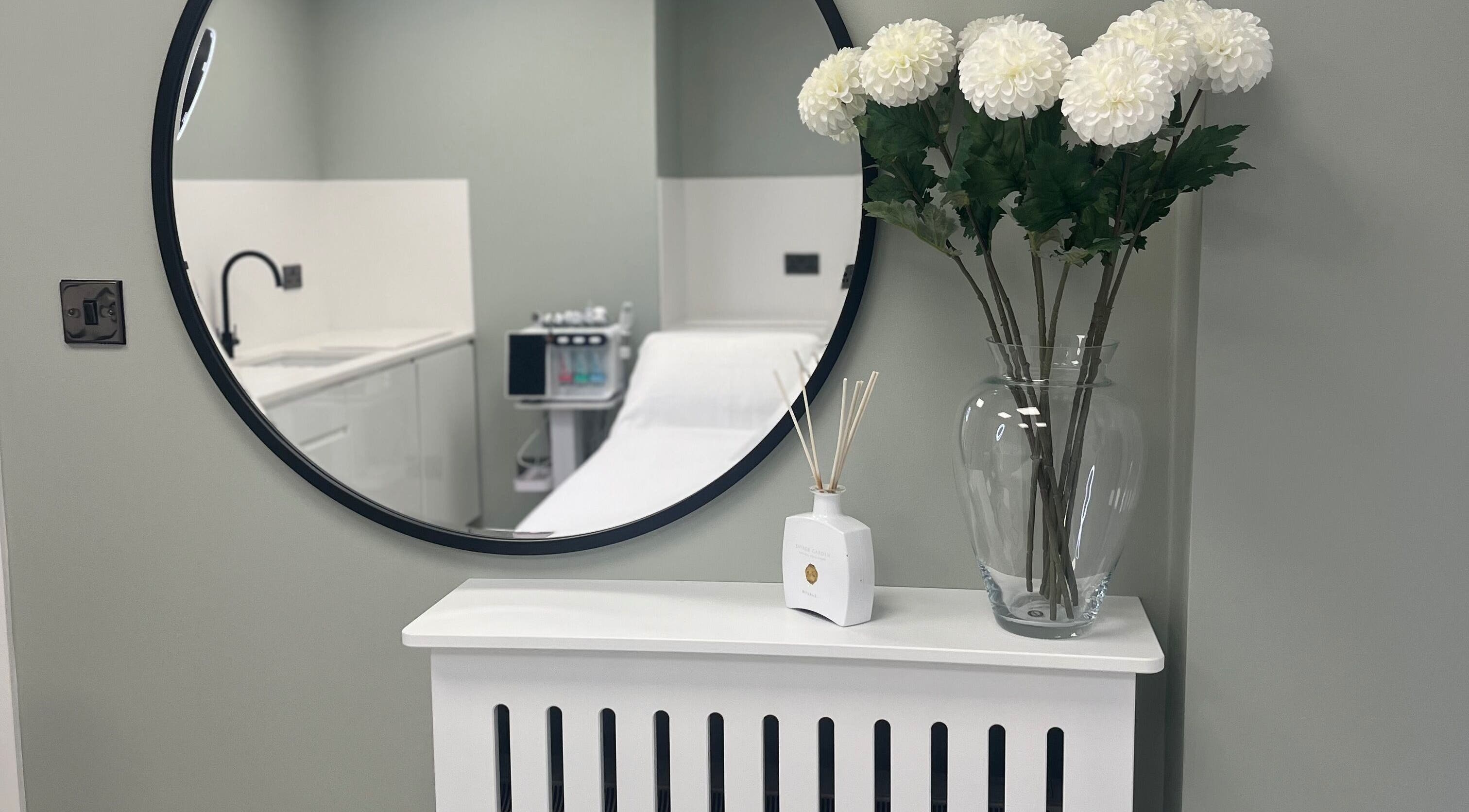 Elegant treatment room at Nisha Sknn Aesthetics & Skin, Londonderry, Northern Ireland, GB featuring a round mirror.