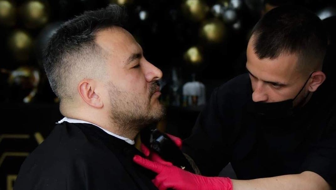 Cliente recibiendo corte de barba en Porium Barbería, Envigado, Antioquia, CO. Profesional cortando con precisión.