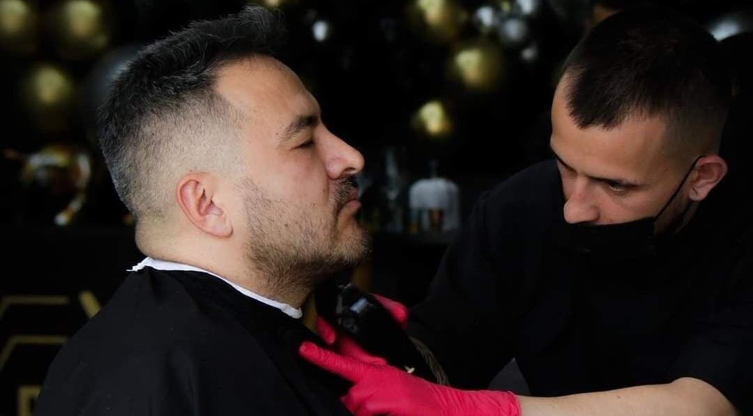 Cliente recibiendo corte de barba en Porium Barbería, Envigado, Antioquia, CO. Profesional cortando con precisión.