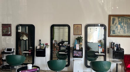 Interior de peluquería en La Nueva Pop, Renedo De Piélagos, Cantabria, ES con espejos elegantes y sillas verdes.