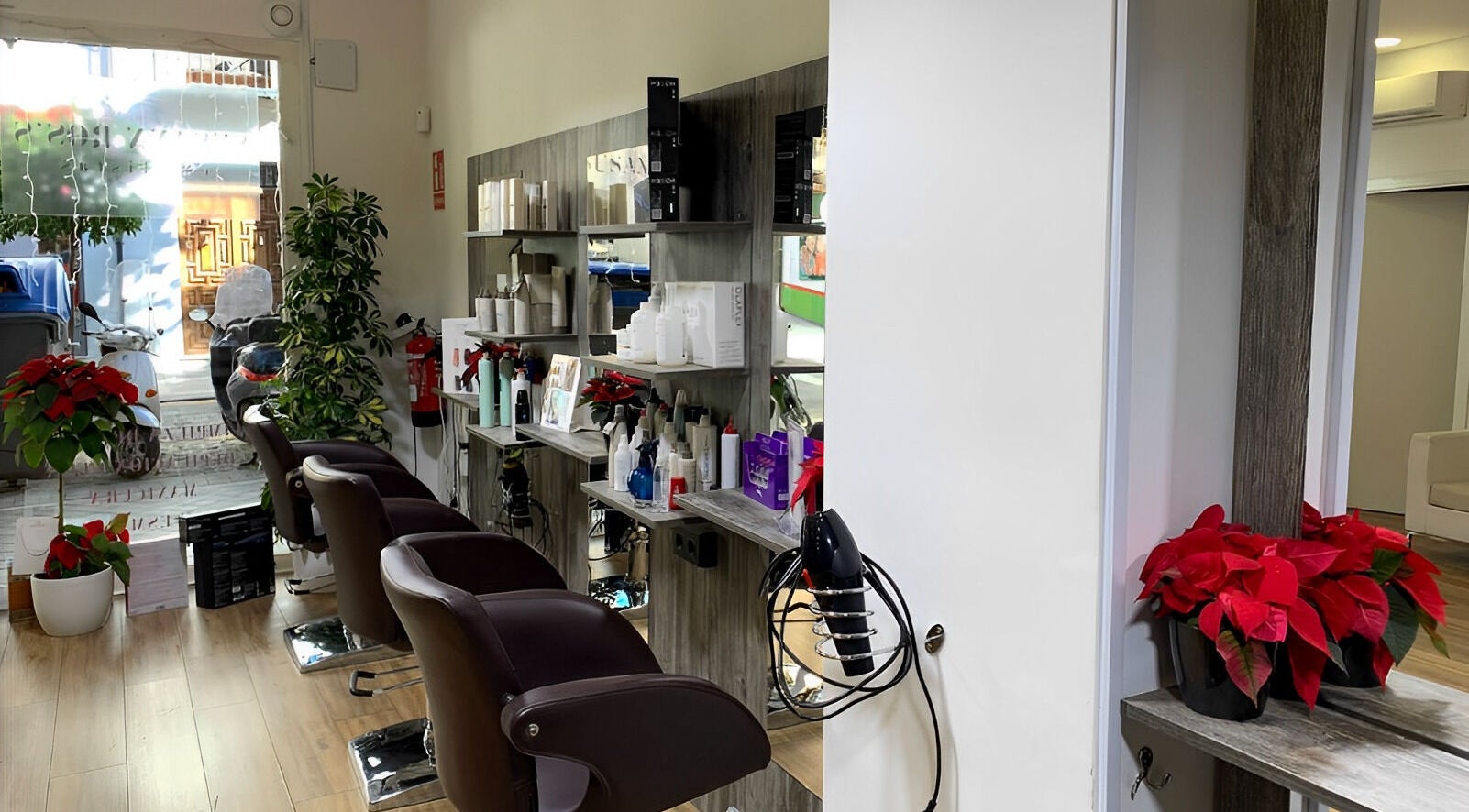 Interior de Susann Ross en Granada, Andalucía, ES, mostrando sillas de peluquería y estantes con productos.