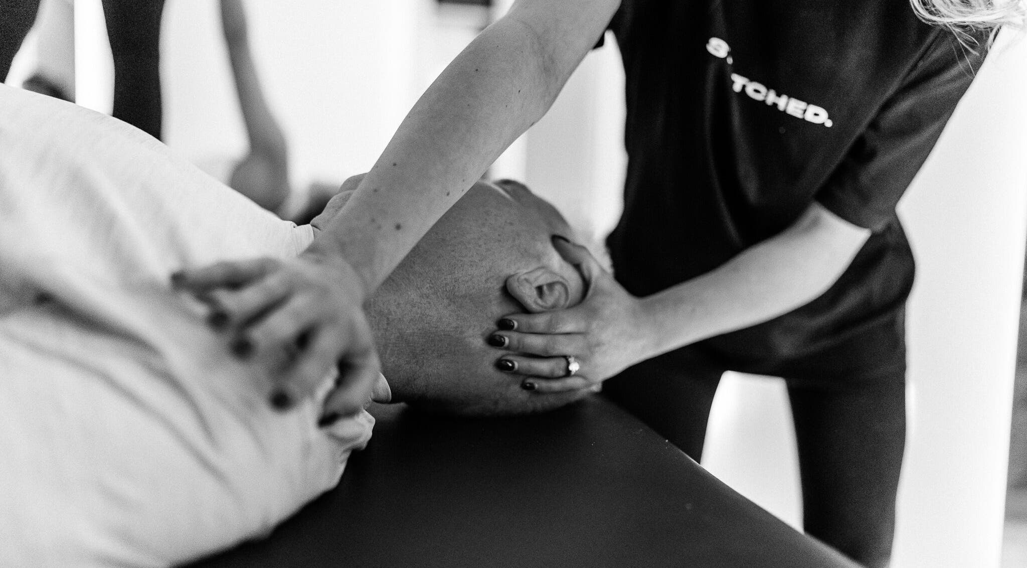 Massage therapy session at Stretched Manchester, Manchester, England, GB. A therapist gently stretches a client's neck.