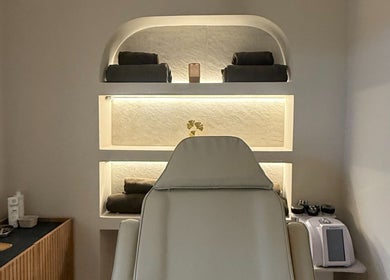 Sala de tratamiento en Zibanna, Madrid, Comunidad De Madrid, ES, con silla blanca y estantería iluminada.