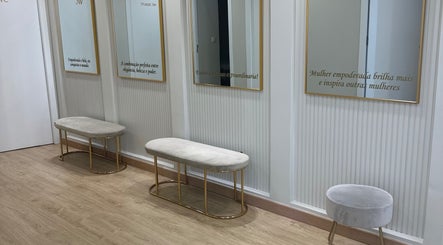 Espaço elegante do Studio Lins Beauty em Lisboa, PT, com bancos luxuosos e espelhos com moldura dourada.