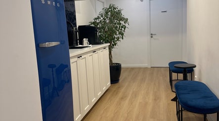 Área de espera estilosa no Studio Lins Beauty, Lisboa, Lisboa, PT com design moderno e frigobar azul.