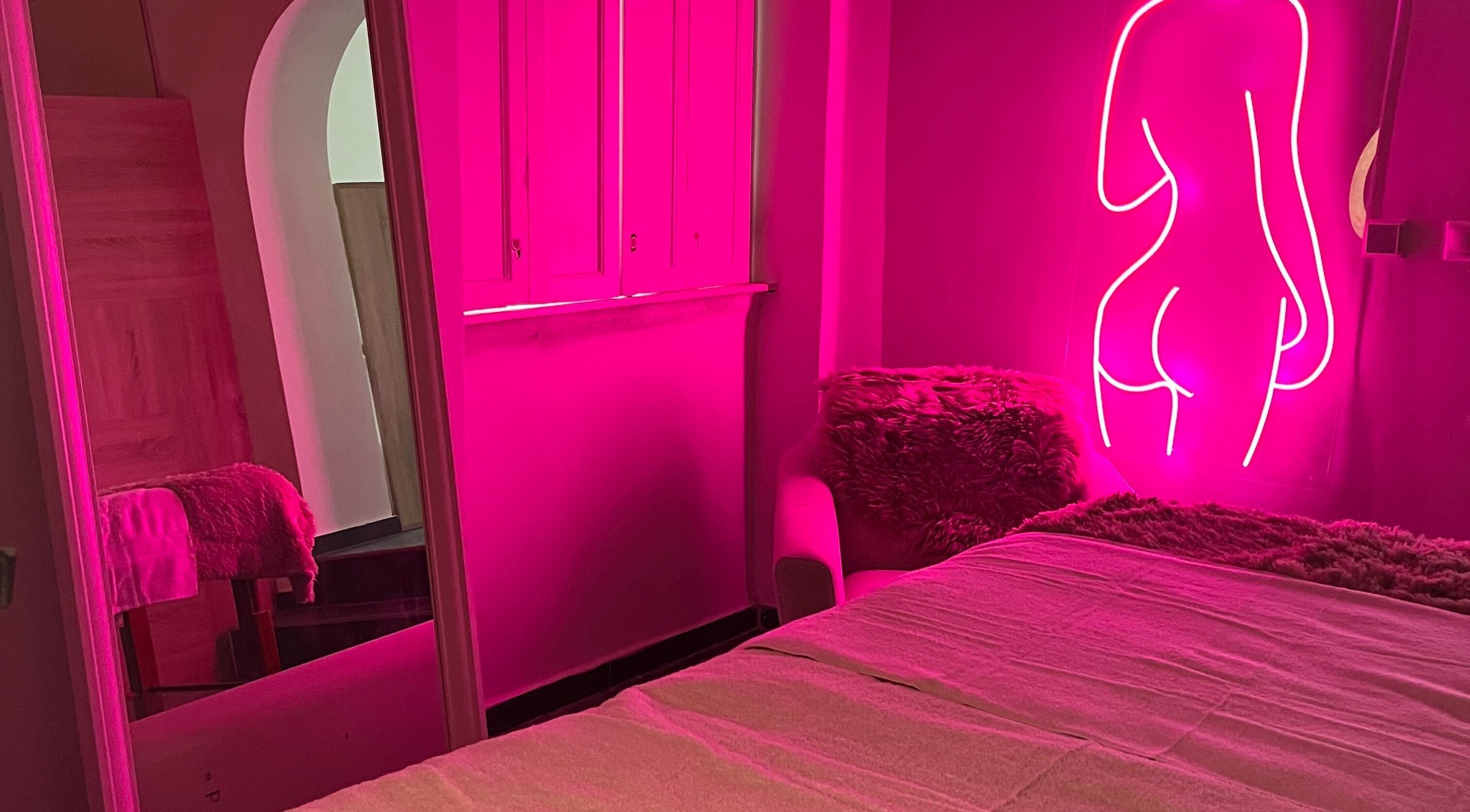 Vibrant pink room at HOLNAPLÀNY, Budapest, Magyar, HU with neon art and cozy decor.