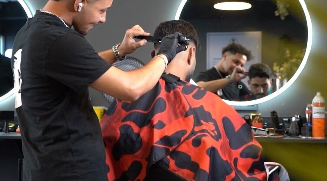 Stylist at The Barber, London, England, GB expertly trims a client's hair in a stylish, modern setting.