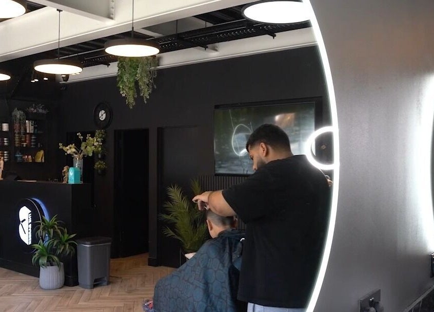 Modern barber shop interior at The Barber in London, England, GB, featuring stylish lighting and skilled hairstylist.