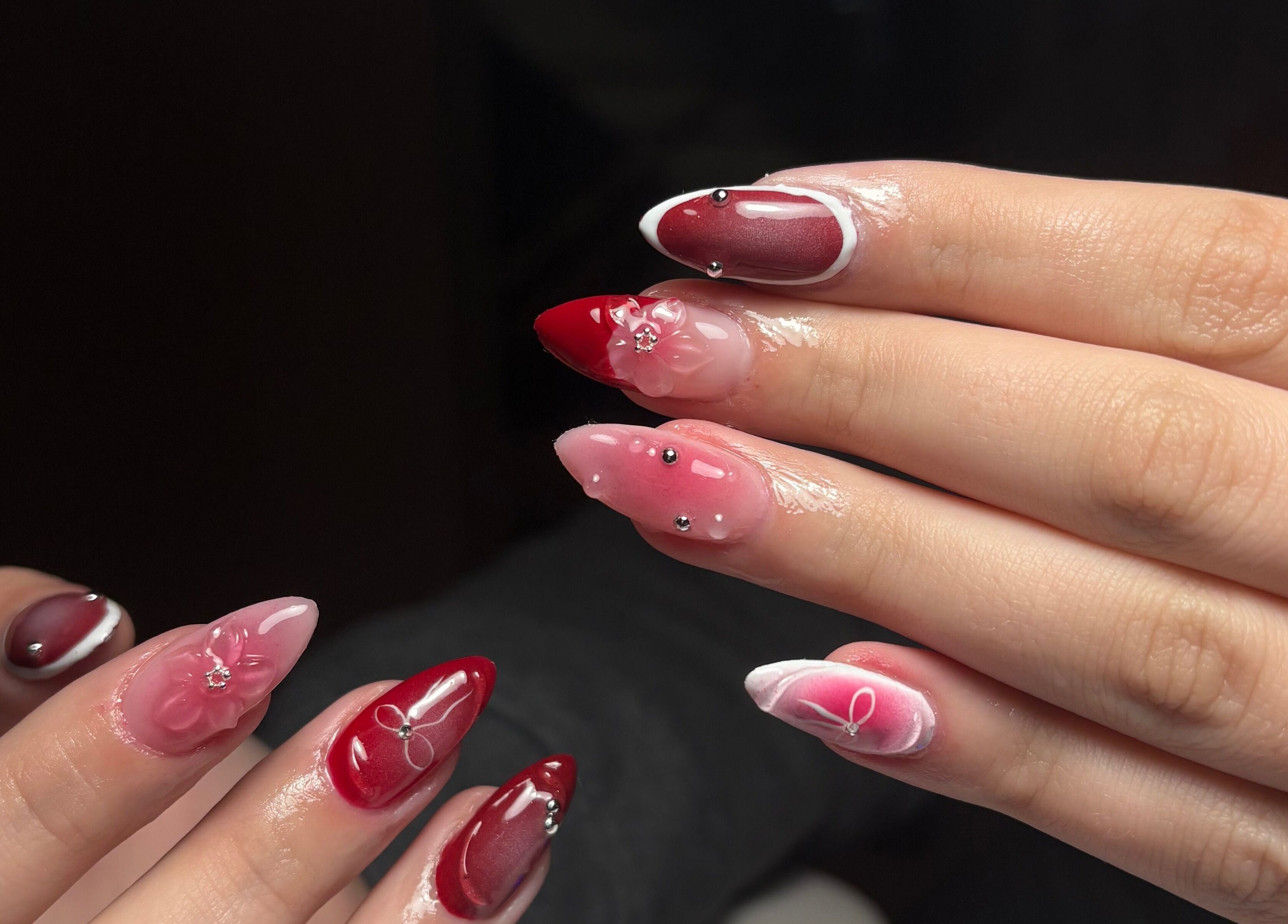Elegant red and pink nail art by Clawed By Chl in Edmonton, Alberta, CA, showcasing intricate designs.