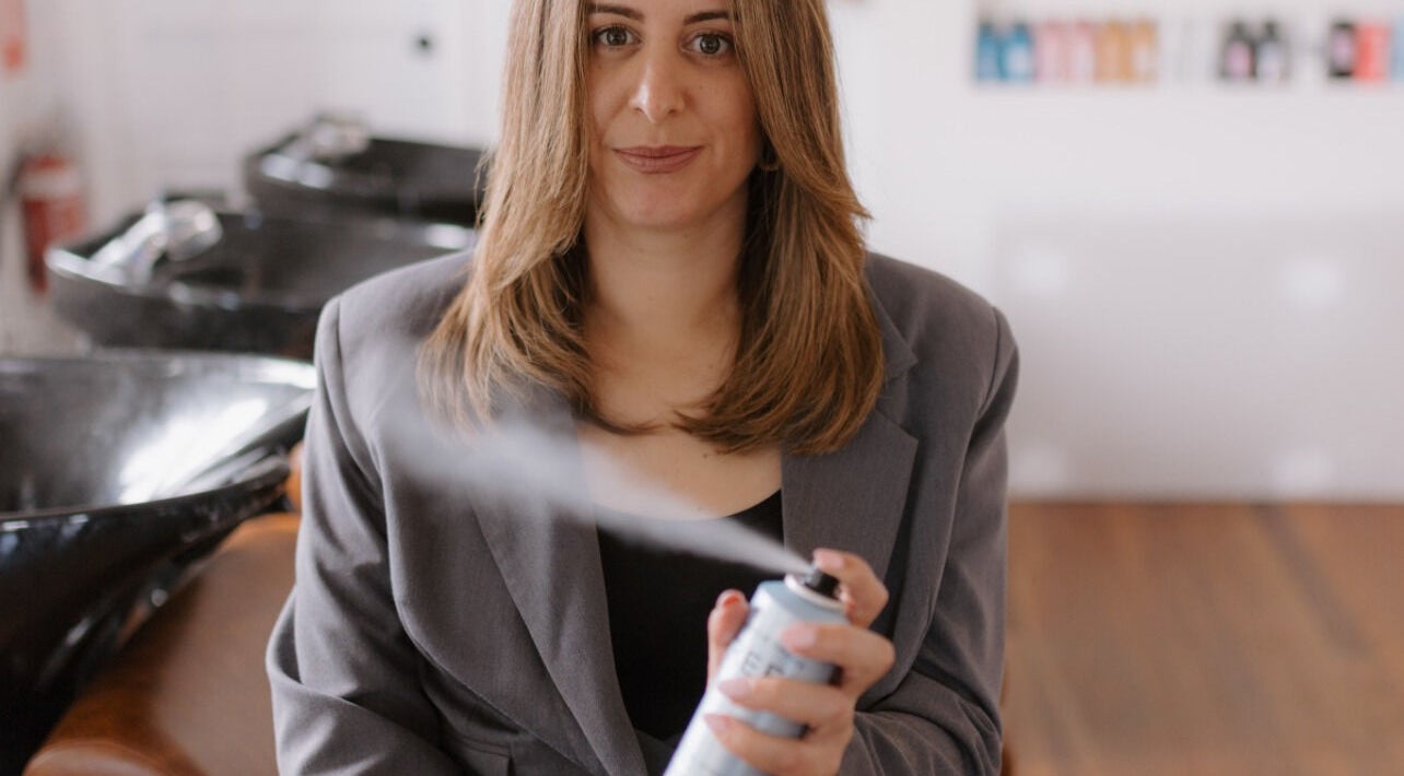 Professional at Hair by Patricia Elena in Mount Hawthorn, WA AU, holding hairspray can in salon setting.