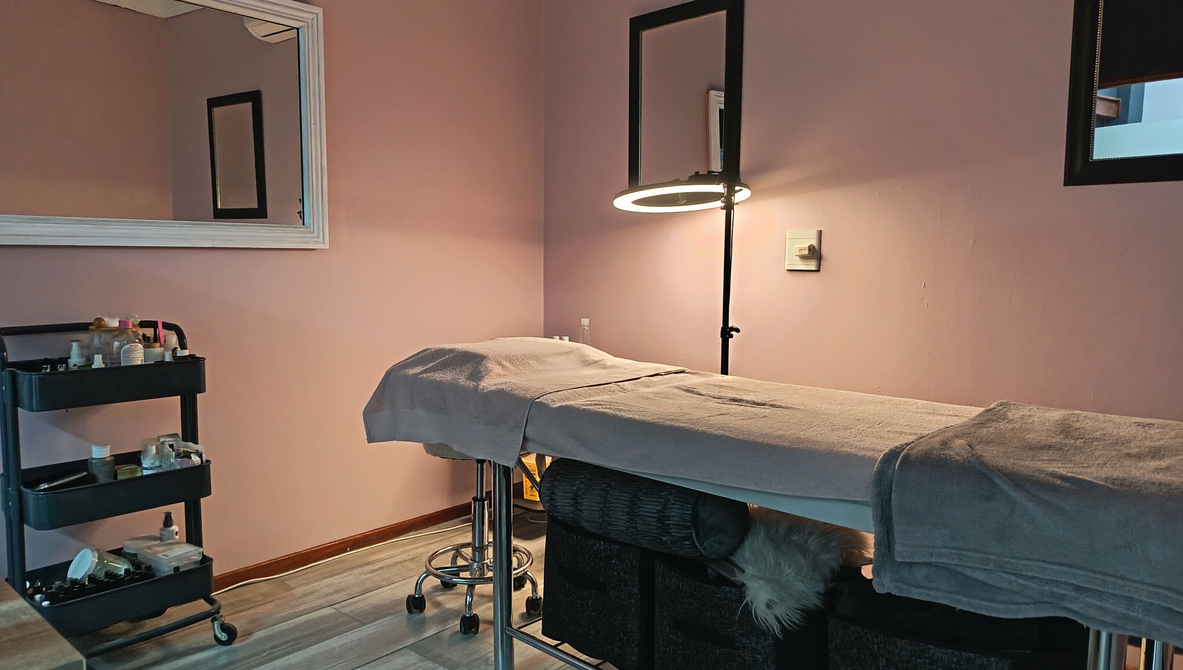 Relaxing treatment room at The Glam Lab, Hartbeespoort, North West, ZA, featuring a massage table and beauty products.