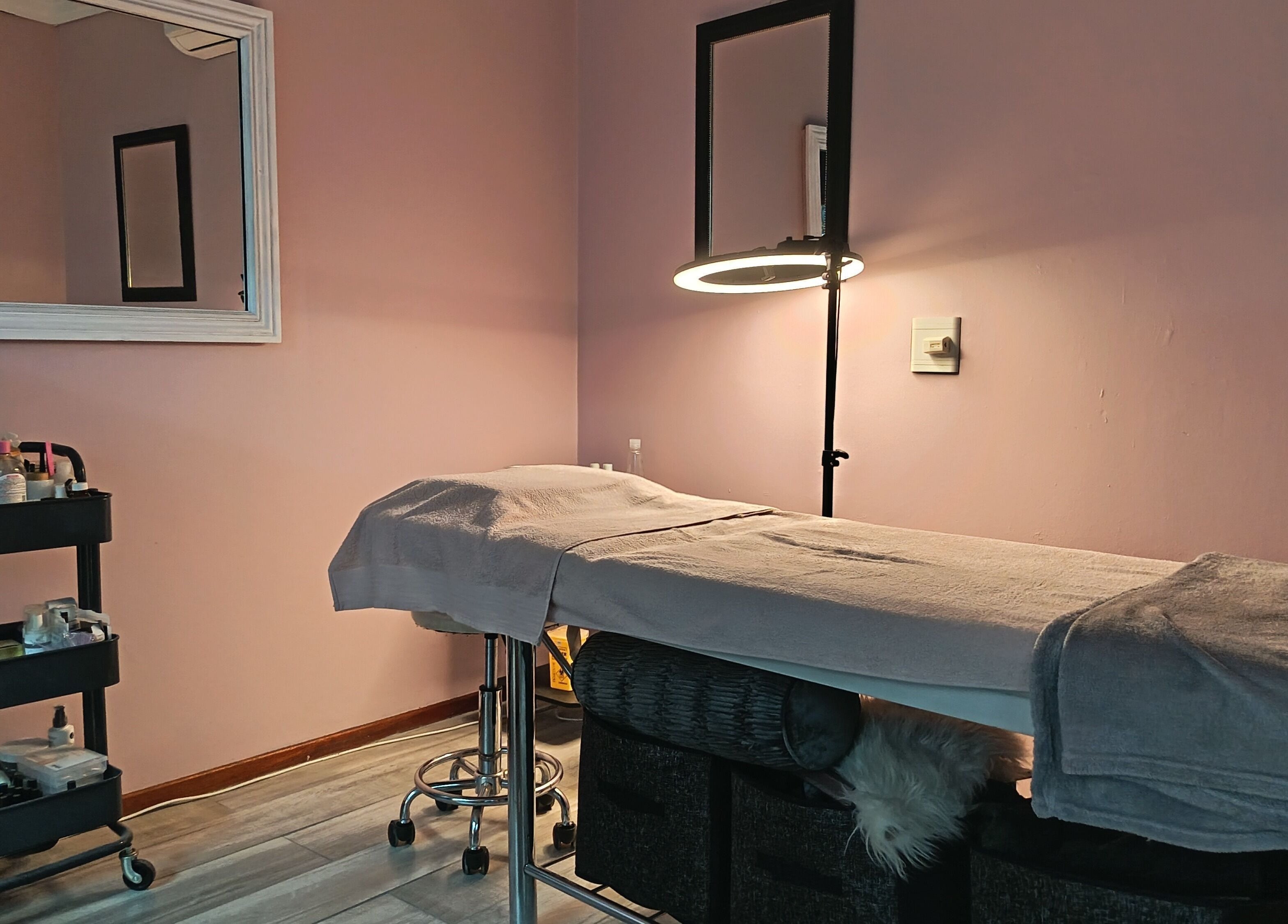 Relaxing treatment room at The Glam Lab, Hartbeespoort, North West, ZA, featuring a massage table and beauty products.