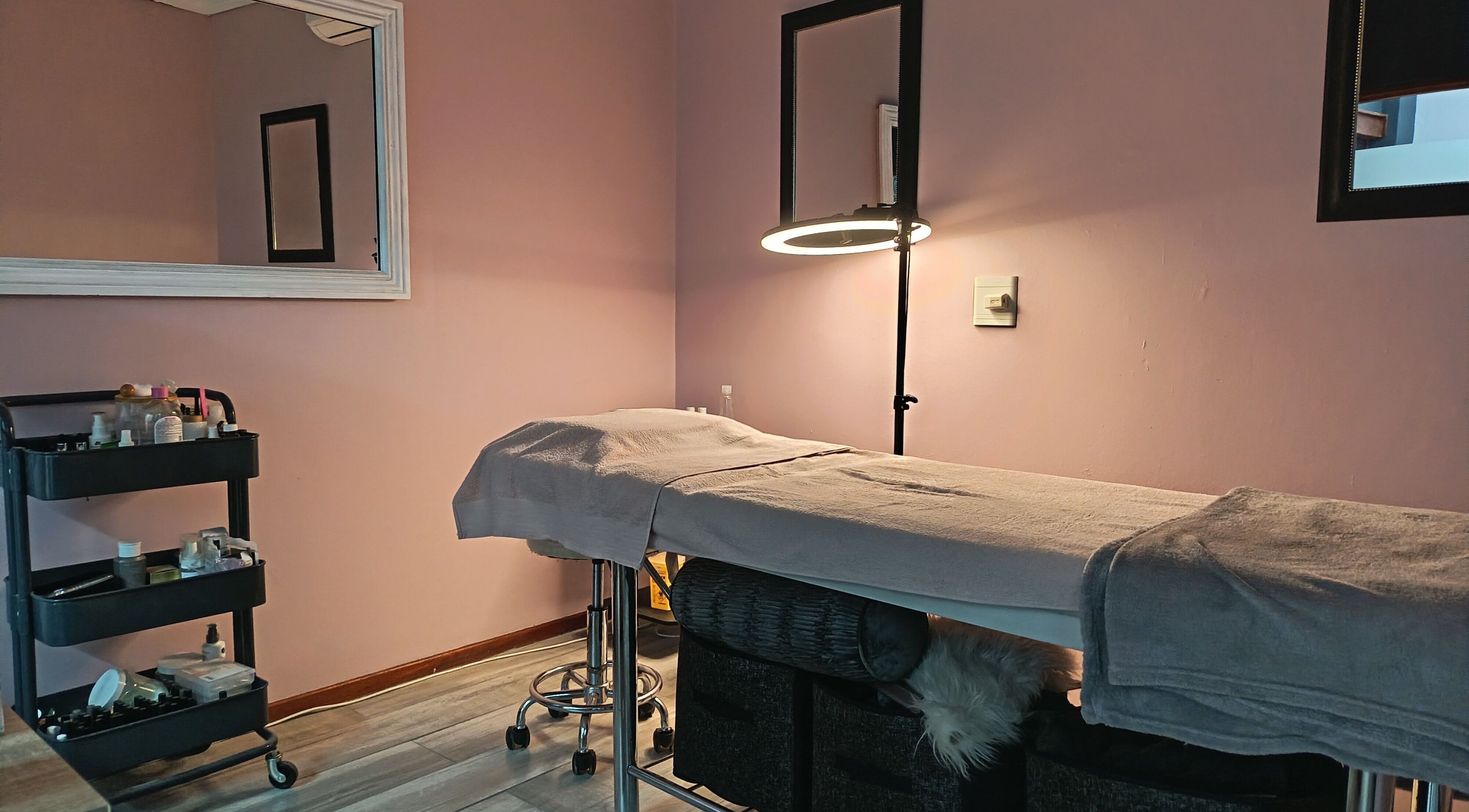 Relaxing treatment room at The Glam Lab, Hartbeespoort, North West, ZA, featuring a massage table and beauty products.