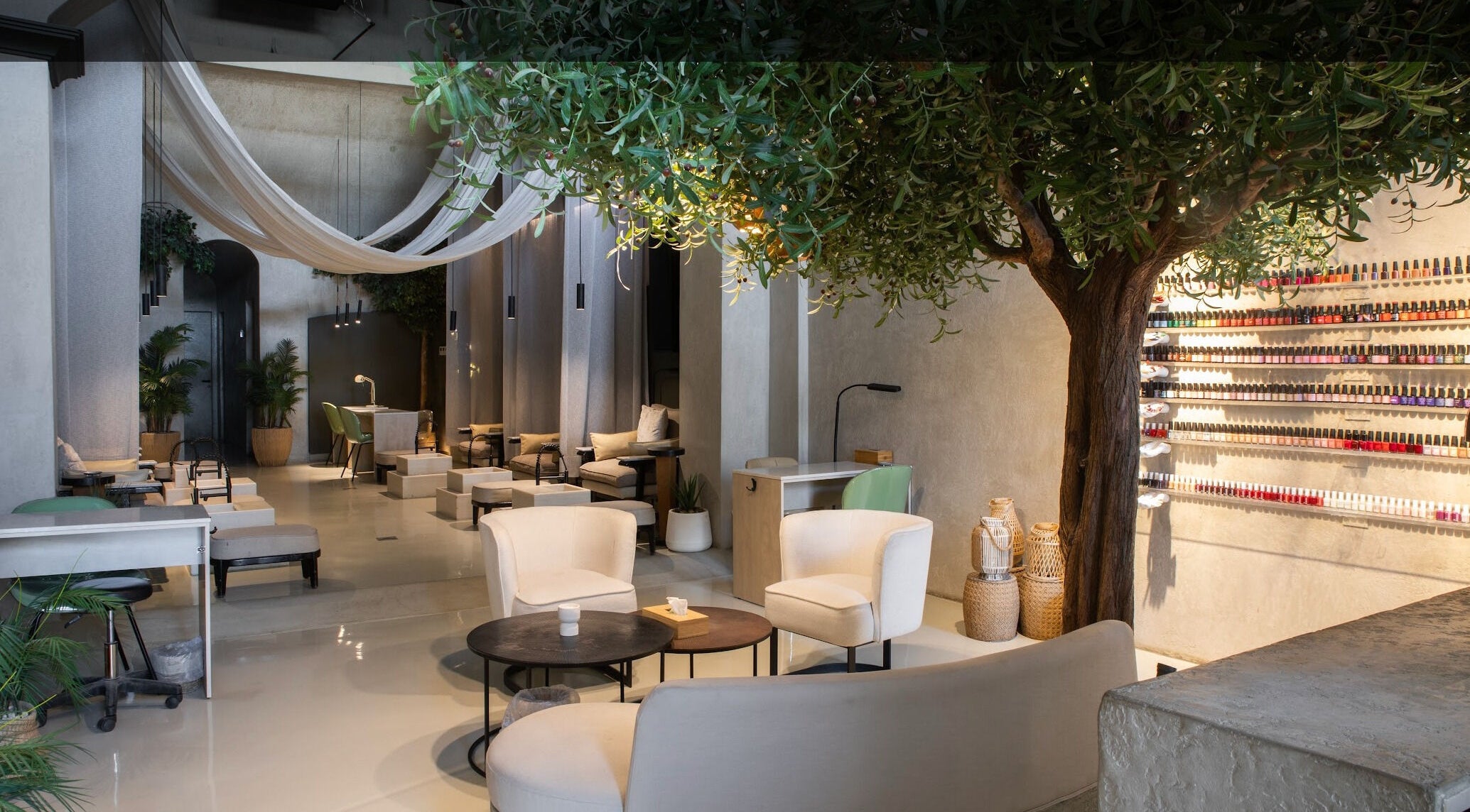 Elegant interior of Nails Aholic - Ar Rahmaniyyah in Riyadh, showcasing chic seating and a vast nail polish display.