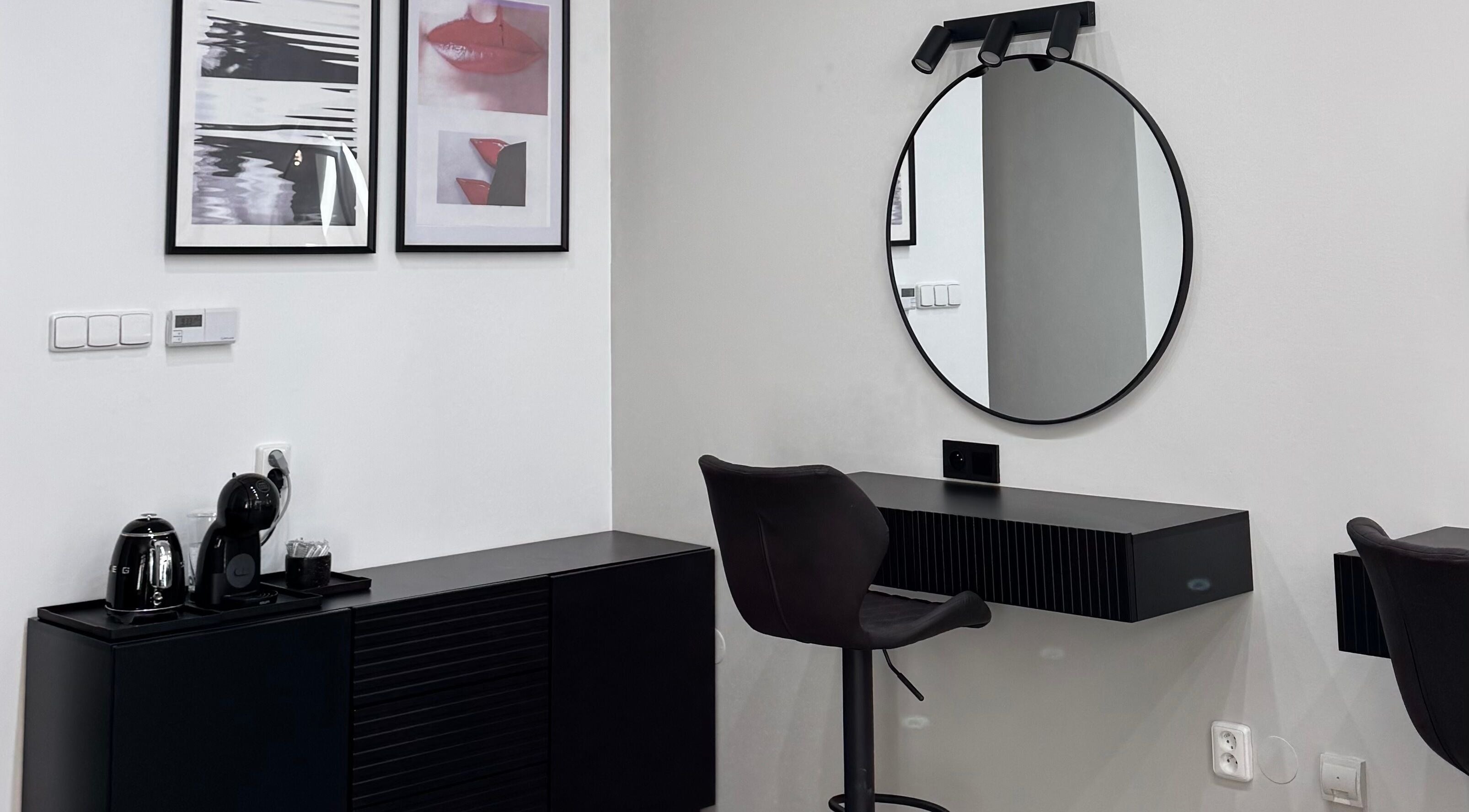 Элегантный уголок студии LENI STUDIO в Hlavní Město Praha с круглым зеркалом и современными картинами.
