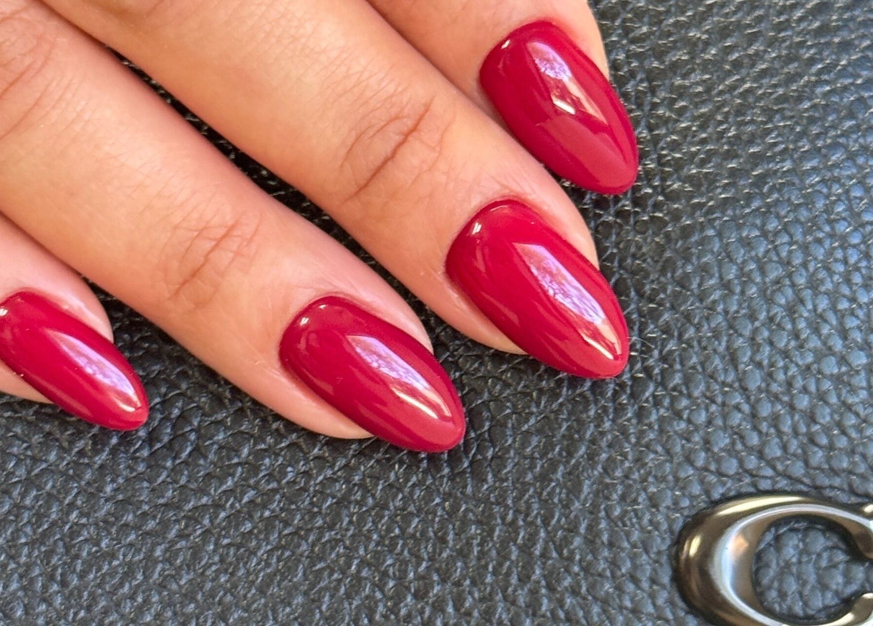 Stylish crimson nails from Dangina Studio, Aurora, Illinois, US on a textured black background.