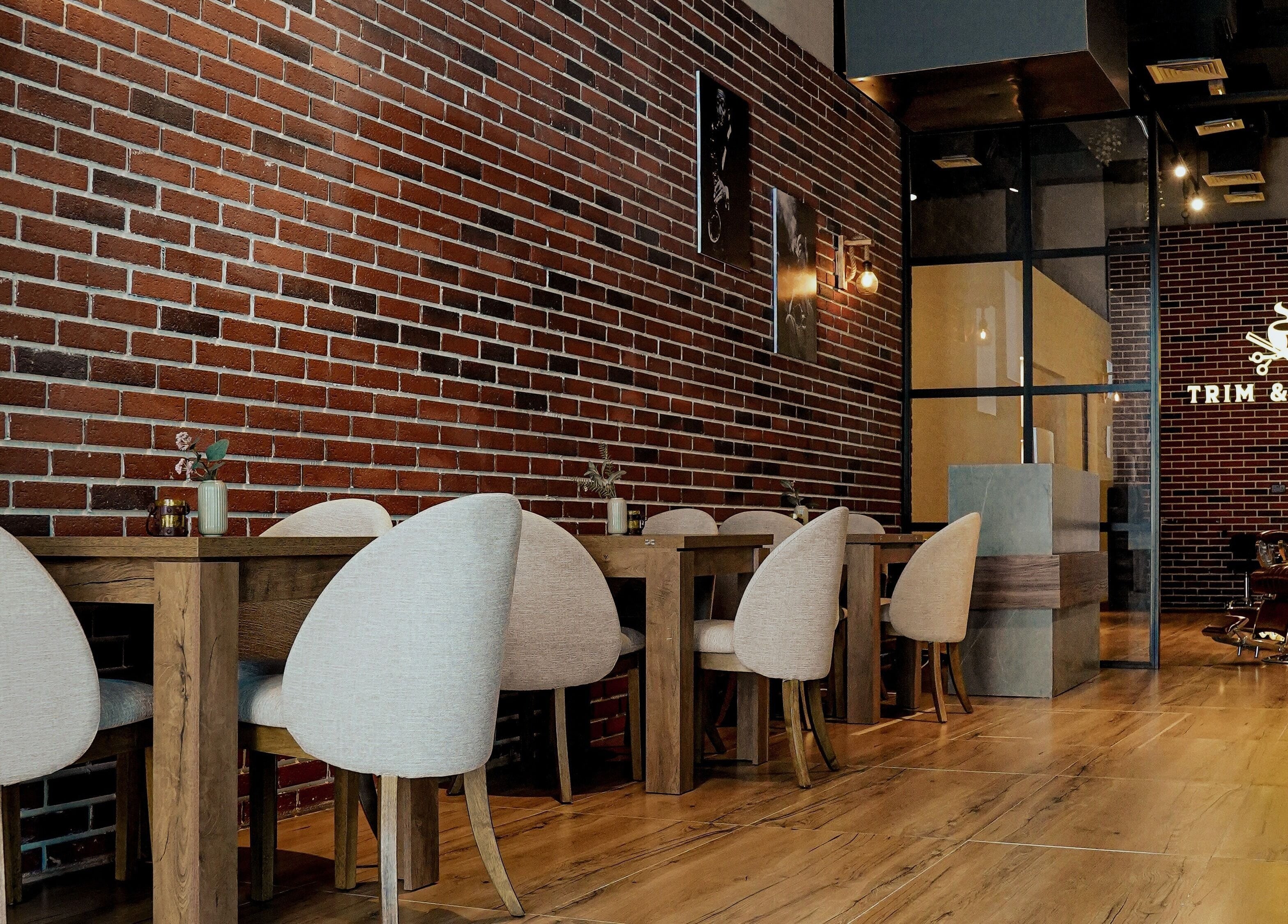 Cozy interior of Trim and Latte Men Hairdressing Trimming and Styling, Abu Dhabi, AE with brick walls and seating.