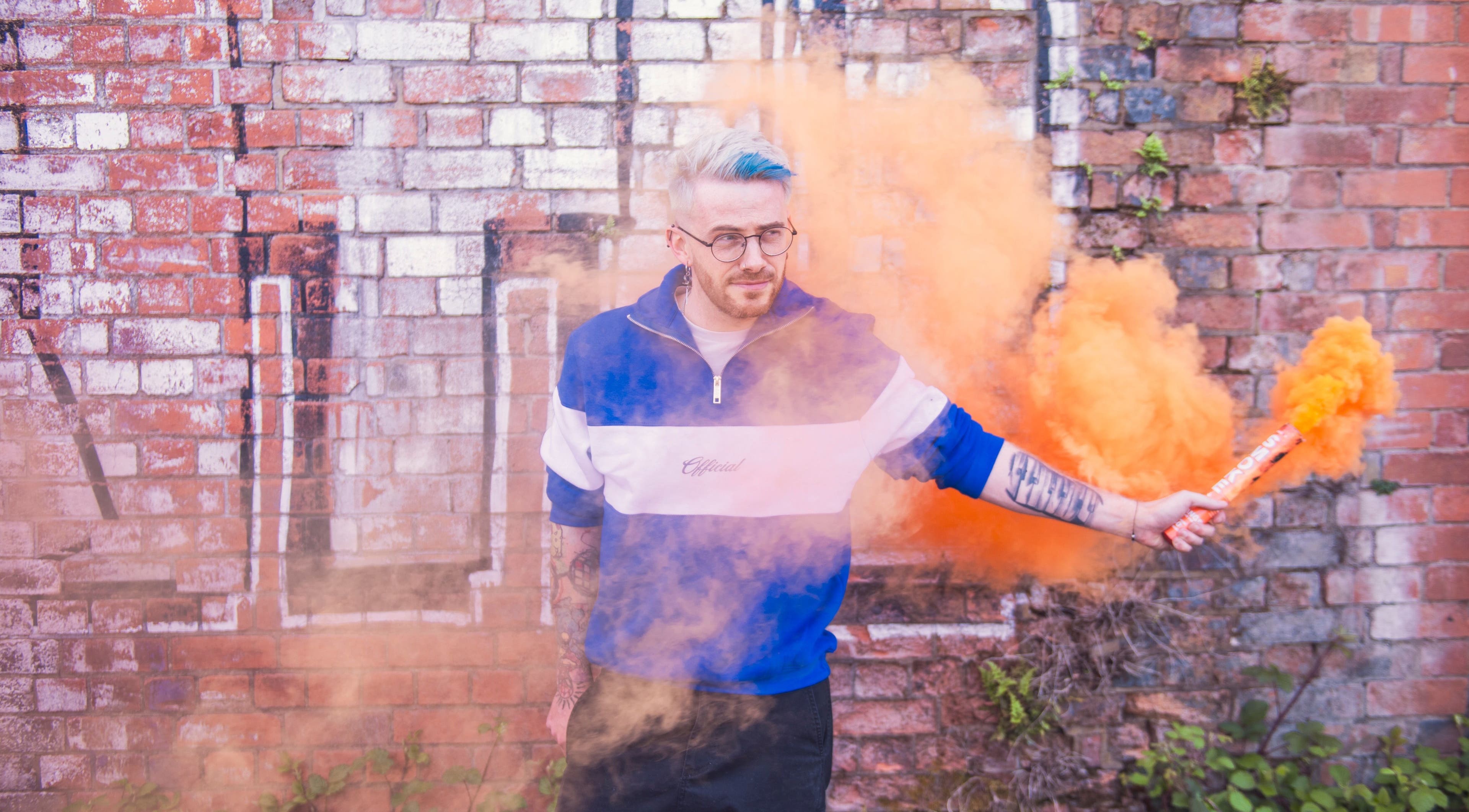 Man holding orange smoke outside Spendlow's Barbering, Newark-on-Trent, England, GB.