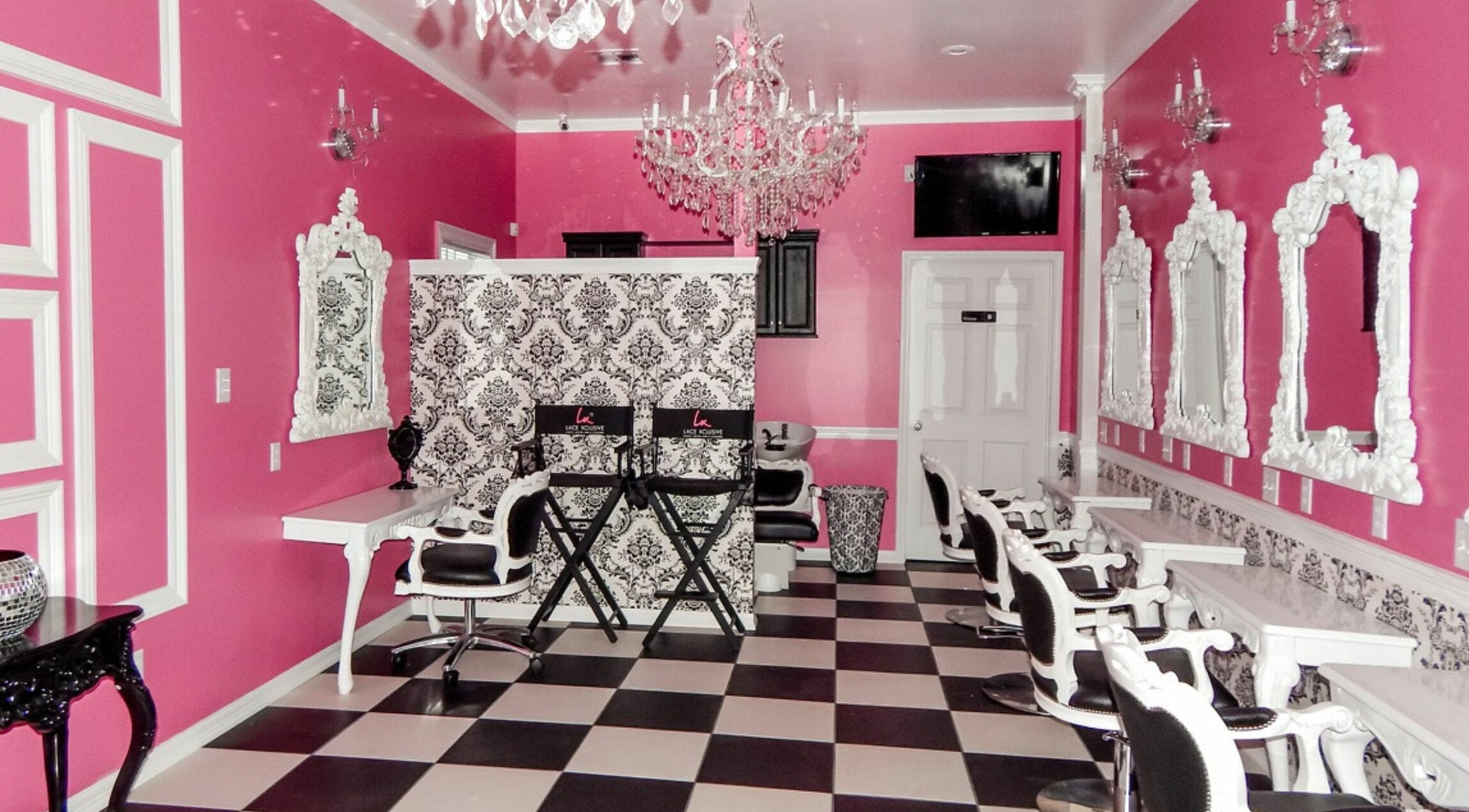 Elegant interior of Lace Xclusive Salon & Spa in New Orleans, Louisiana, US with pink walls and ornate mirrors.