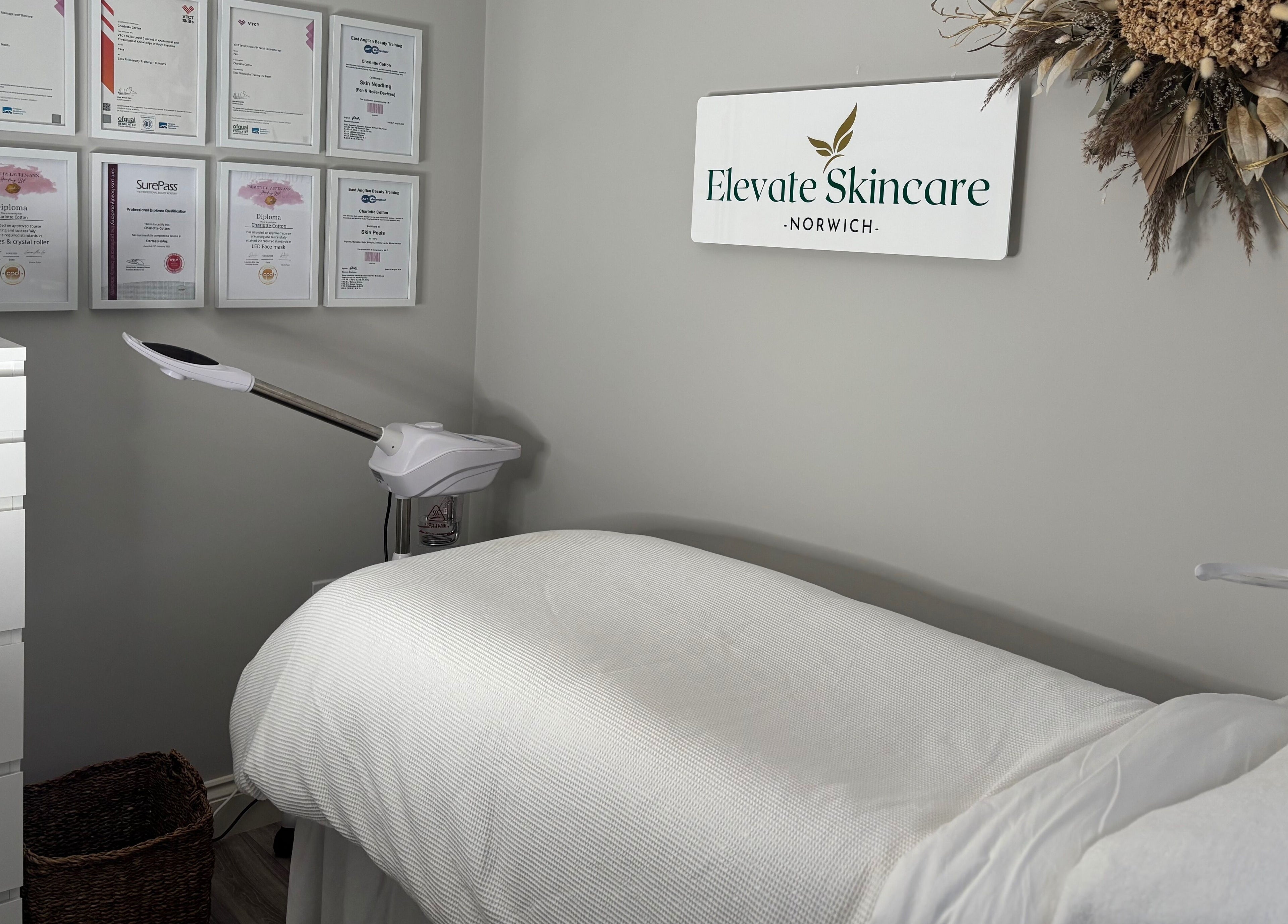 Calm treatment room at Elevate Skincare Norwich, Norwich, England, GB, with bed, diplomas, and decor.