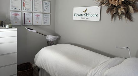 Calm treatment room at Elevate Skincare Norwich, Norwich, England, GB, with bed, diplomas, and decor.