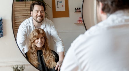 Hairstylist with client in mirror smiling at Les Coupes de Mathieu, Montréal, Québec, CA.