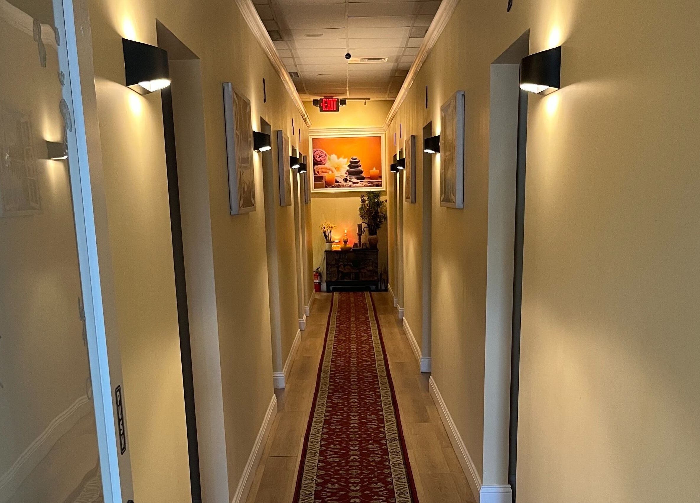 Serene hallway at NY Massage at Riverview, Gibsonton, Florida, US, featuring warm lighting and a red carpet.