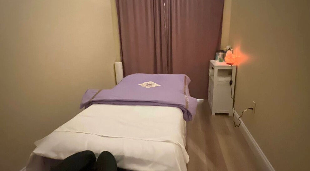 Cozy massage room at NY Massage at Riverview in Gibsonton, Florida, US, featuring a neatly made bed and soft lighting.