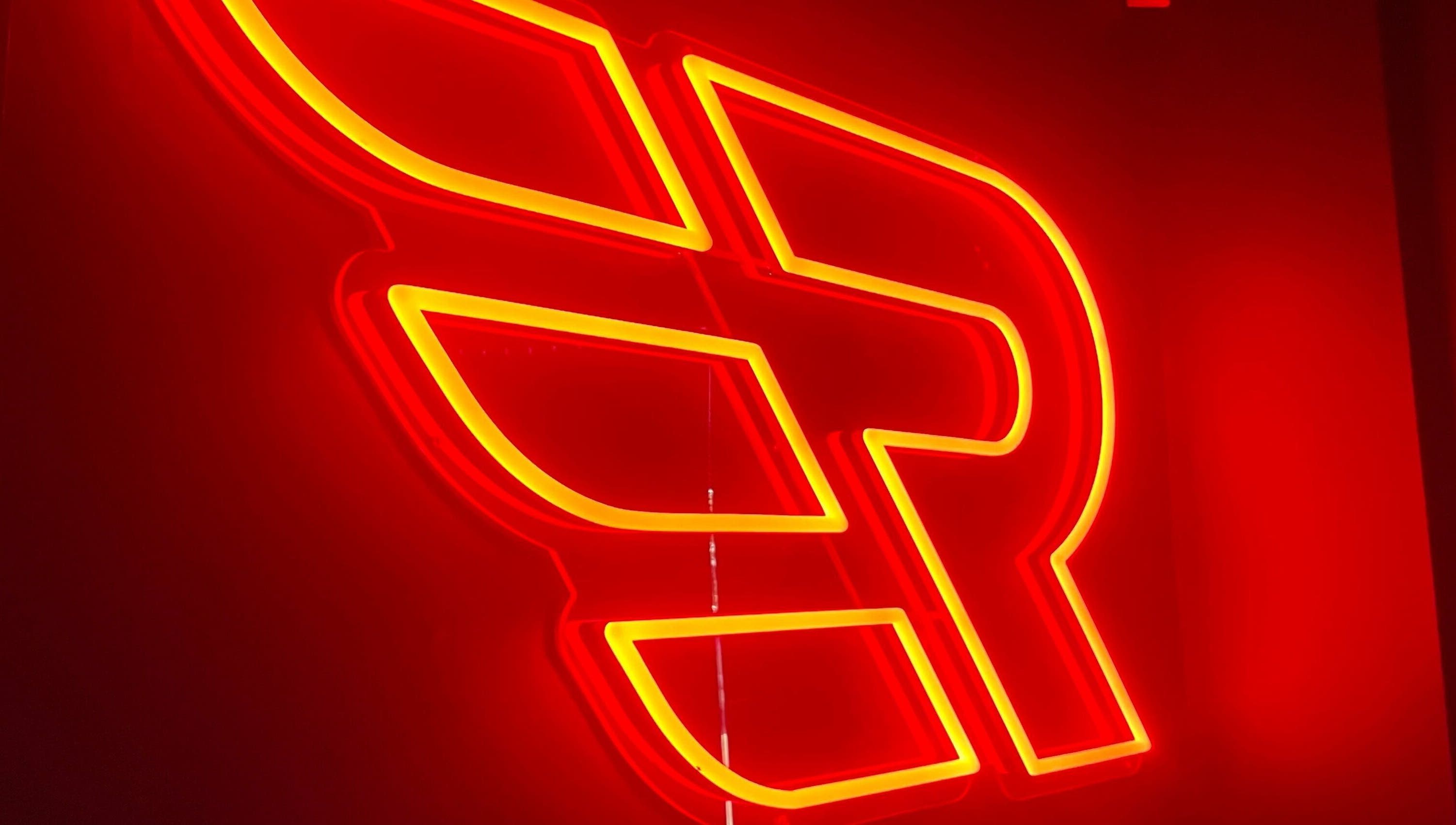 Neon sign at Engineroom Barbers in Fountaindale, New South Wales, AU, glowing in warm red and yellow hues.
