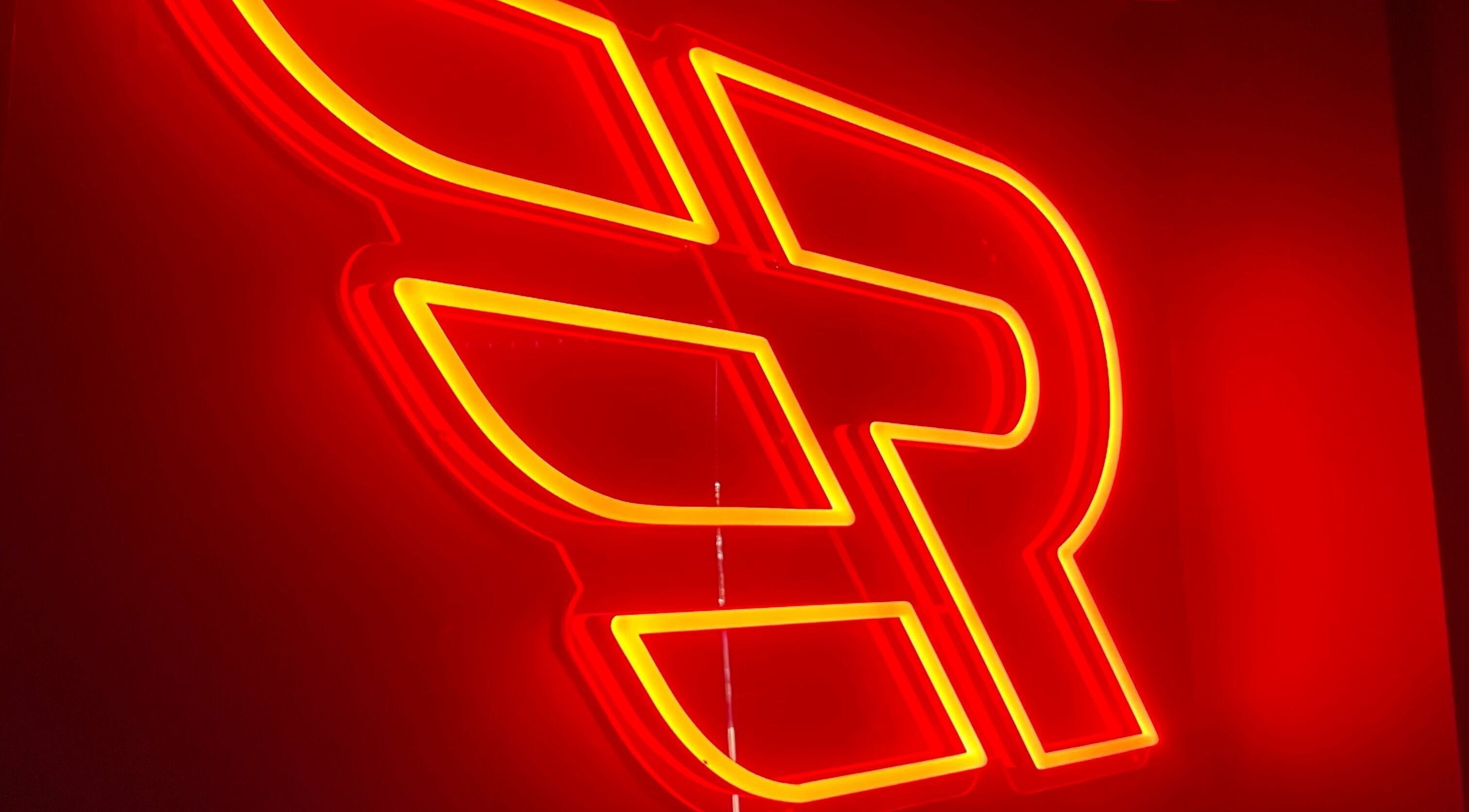 Neon sign at Engineroom Barbers in Fountaindale, New South Wales, AU, glowing in warm red and yellow hues.