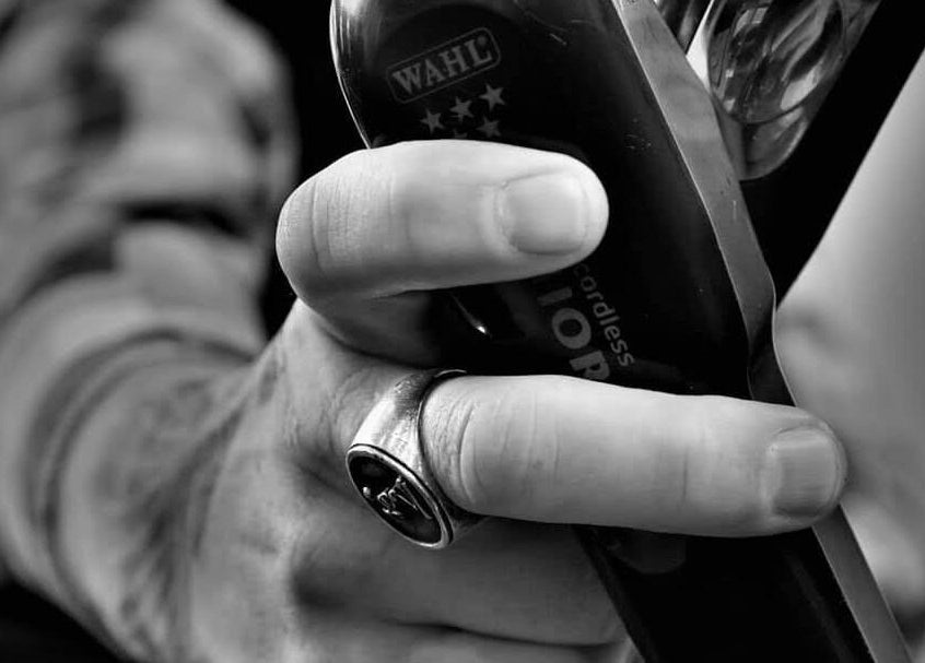 Expert hand holding clippers at The Salty Barber, Manawatū-whanganui, NZ, showcasing skilled grooming.